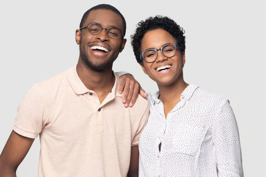 A smiling man and woman, both wearing glasses.