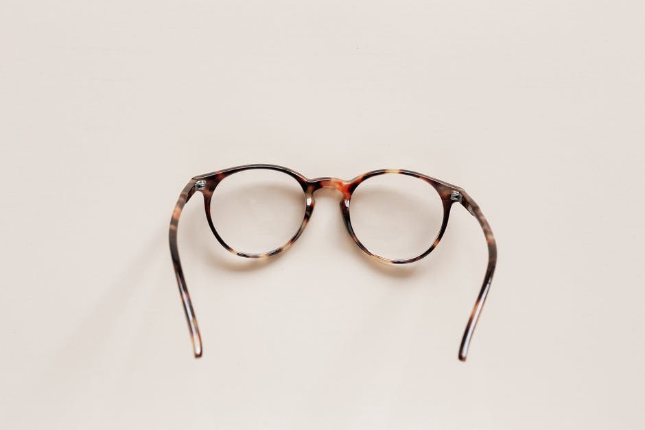 A pair of tortoiseshell glasses against an ivory-colored background.