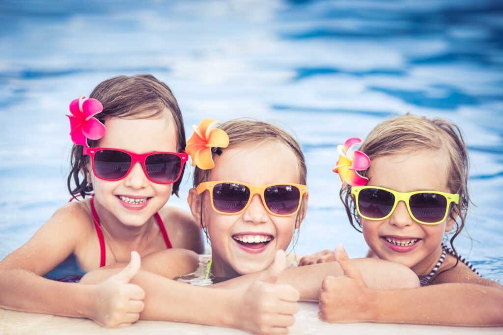 A group of kids wearing sunglasses and smiling at the camera Description automatically generated with medium confidence